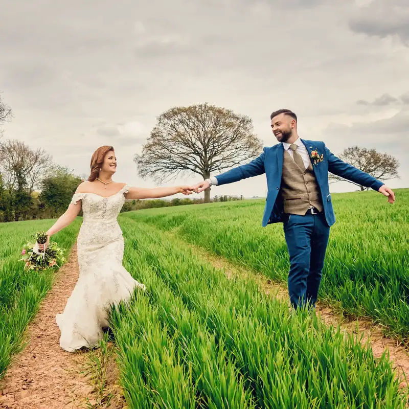 Newlyweds holding hands in a Worcestershire meadow Newlyweds holding hands in a Worcestershire meadow